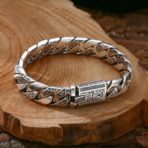 Thick silver Cuban link bracelet displayed on wooden background