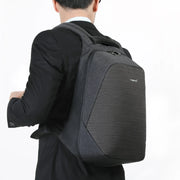 Man wearing a black-grey anti-theft laptop backpack, showing its slim ergonomic shape and comfortable padded straps for daily commuting.
