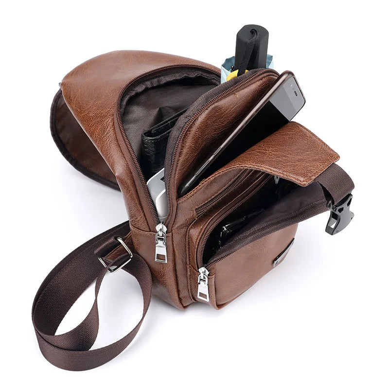Open brown leather sling bag displaying spacious compartments filled with a phone and small accessories.