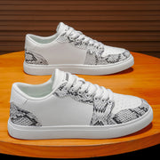 White men's fashion sneakers with snake print detail and thick sole on wooden table