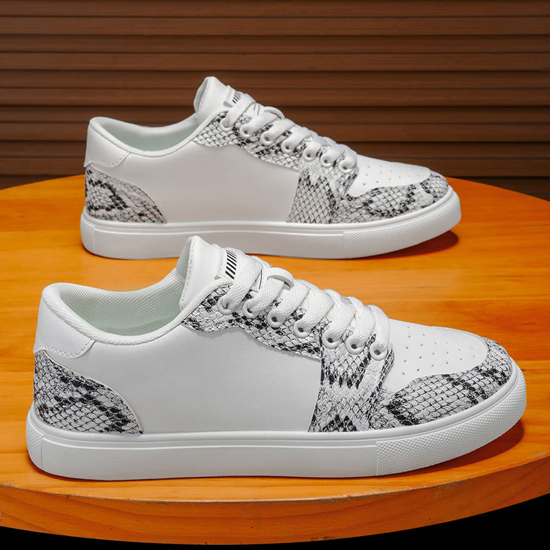White men's fashion sneakers with snake print detail and thick sole on wooden table