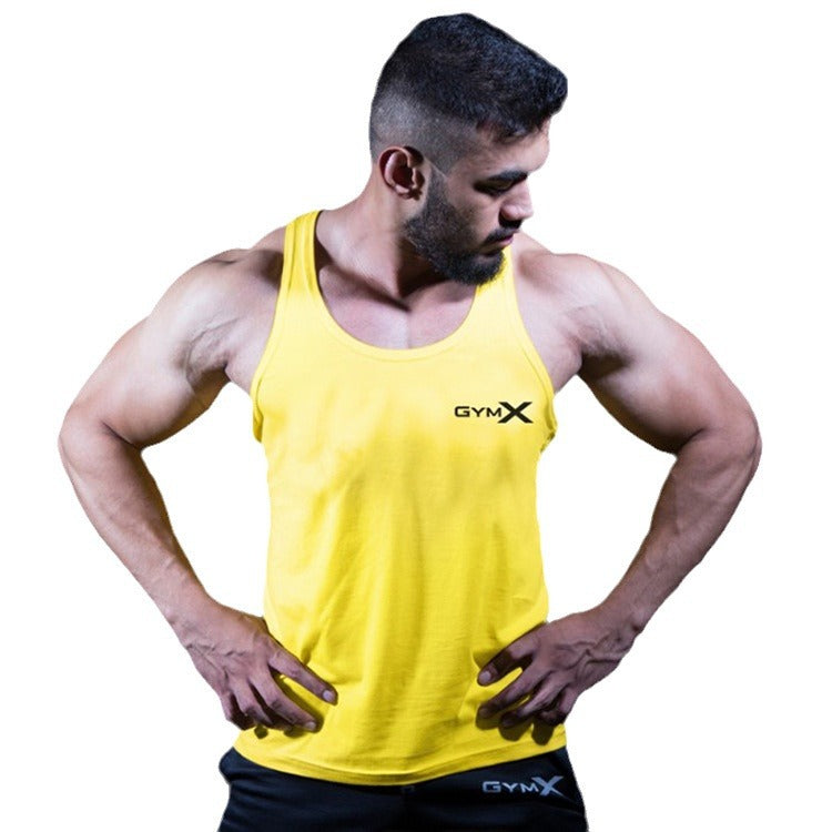 Man in a yellow GymX sleeveless fitness tank top posing with hands on hips, showing athletic upper body definition.
