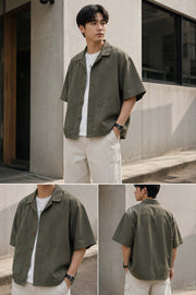 Oversized army green Japanese workwear Cuban collar shirt shown on a male model with front, side, and back views, featuring rounded patch pockets and relaxed streetwear styling.