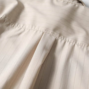 Back pleat detail of beige retro loose fit short sleeve button-up shirt showing relaxed fit construction.
