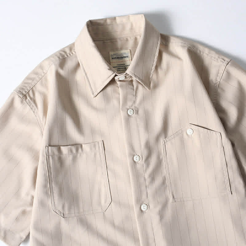 Functional chest pocket detail on beige retro loose fit short sleeve button-up shirt.

