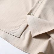 Close-up of hem stitching and fabric finish on beige retro loose fit short sleeve shirt.
