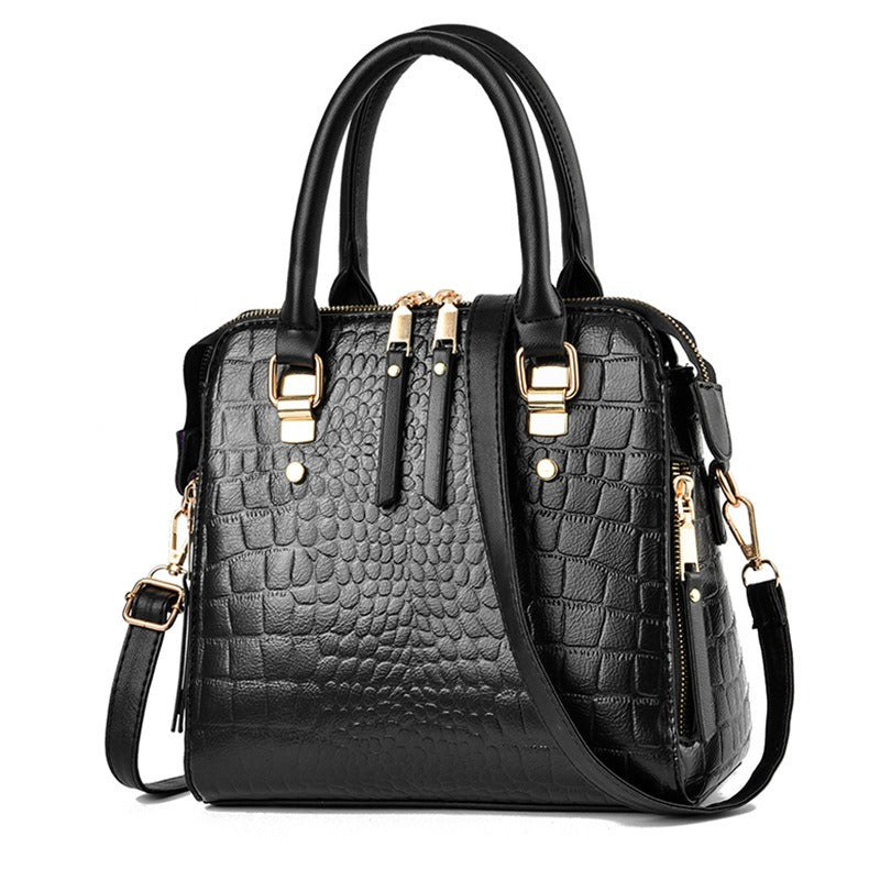Black crocodile embossed handbag with top handles and adjustable shoulder strap
