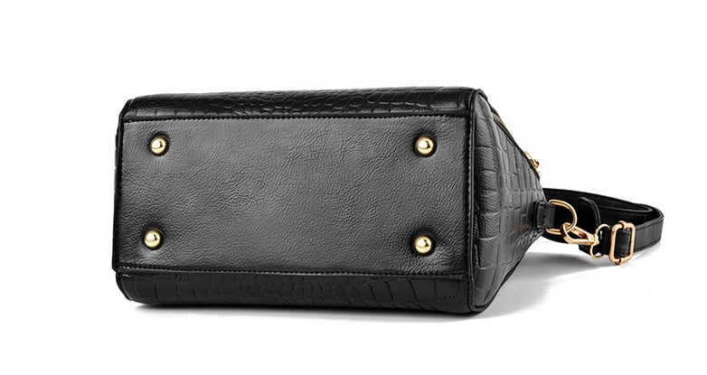 Bottom view of black crocodile texture handbag with protective metal feet for durability
