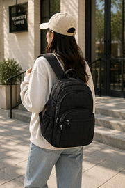 Woman carrying a black quilted backpack outdoors, highlighting a modern and versatile backpack for daily commuting and casual wear.
