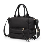 Angled view of a black quilted puffer tote bag with adjustable shoulder strap.
