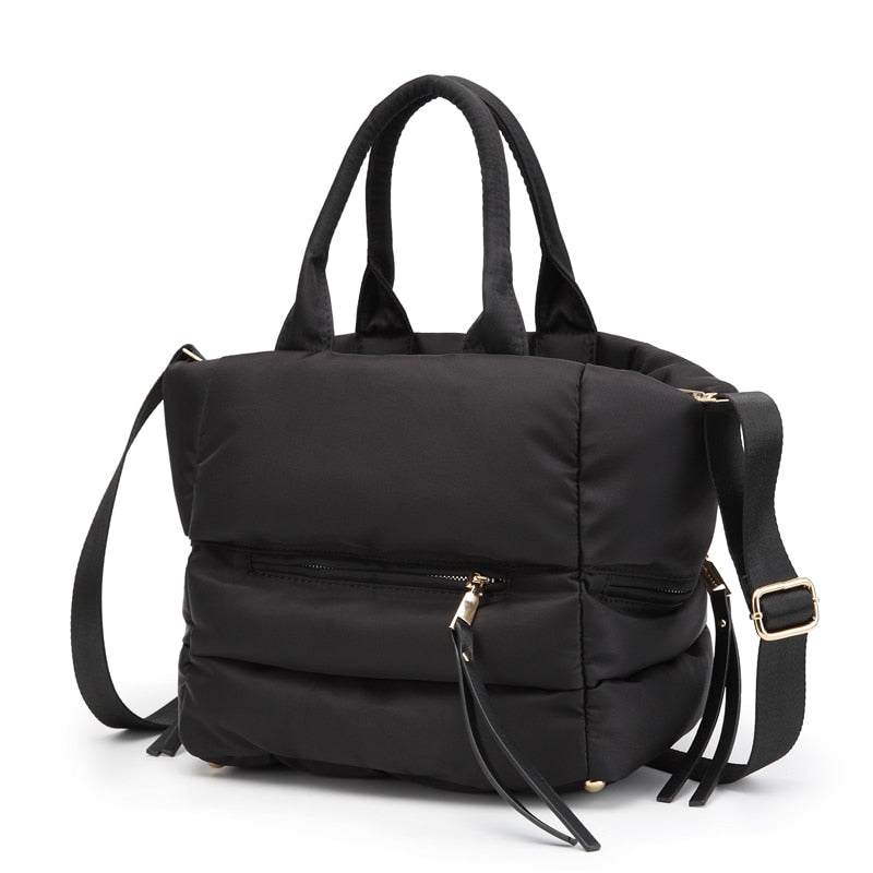 Angled view of a black quilted puffer tote bag with adjustable shoulder strap.
