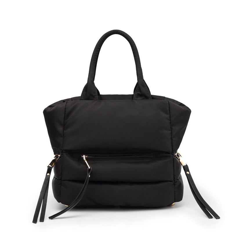 Front view of a black winter puffer tote bag with zippered pocket and padded quilted design.
