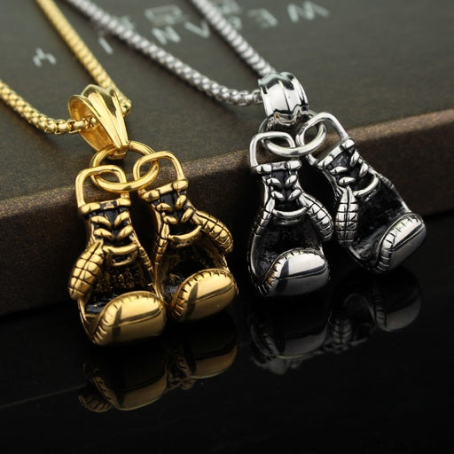 Gold and silver boxing gloves necklace pendant close up on dark background
