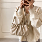 Beige cloud soft shoulder bag paired with a cozy knit cardigan for a soft and feminine casual outfit.
