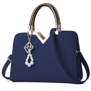 Elegant navy blue women's handbag with gold top handle and adjustable shoulder strap
