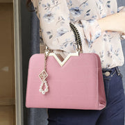 Elegant pink women's handbag with shoulder strap and gold handle detail
