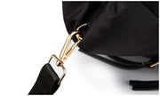 Gold-tone shoulder strap clip attachment on a black quilted tote bag.
