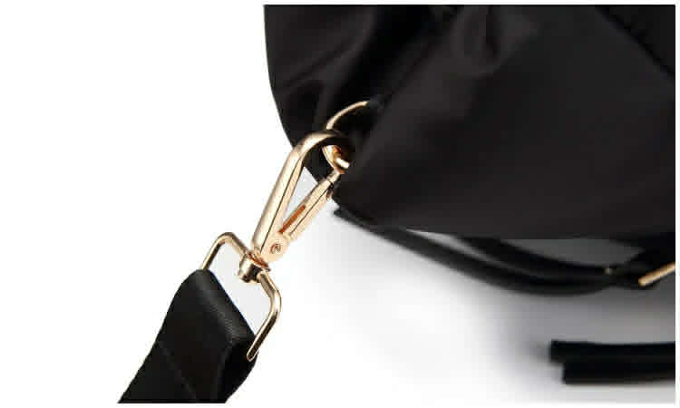 Gold-tone shoulder strap clip attachment on a black quilted tote bag.
