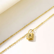 Gold iitial lock necklace with letter A pndant shown at an angle on soft background