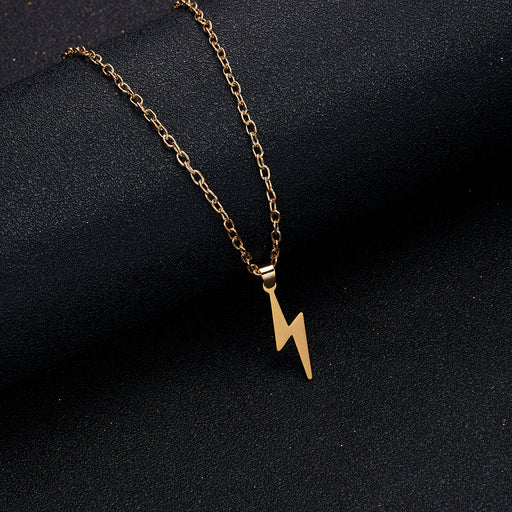 Detailed view of gold lightning bolt pendant necklace with stainless steel chain on dark background