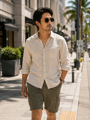Man walking through a city street wearing vintage round sunglasses and casual summer outfit.
