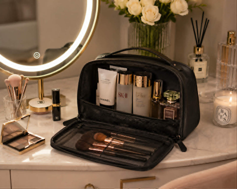 Travel cosmetic bag displayed on a vanity table with organized makeup brushes, skincare products, and beauty essentials.
