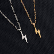 Gold and silver lightning bolt pendant necklaces with minimalist stainless steel chains on black textured background