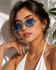 Woman wearing blue lens luxury rimless sunglasses with gold frame in a clean luxury fashion portrait
