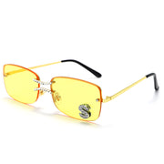 Yellow lens square rimless sunglasses with gold metal frame and crystal S accent on white background
