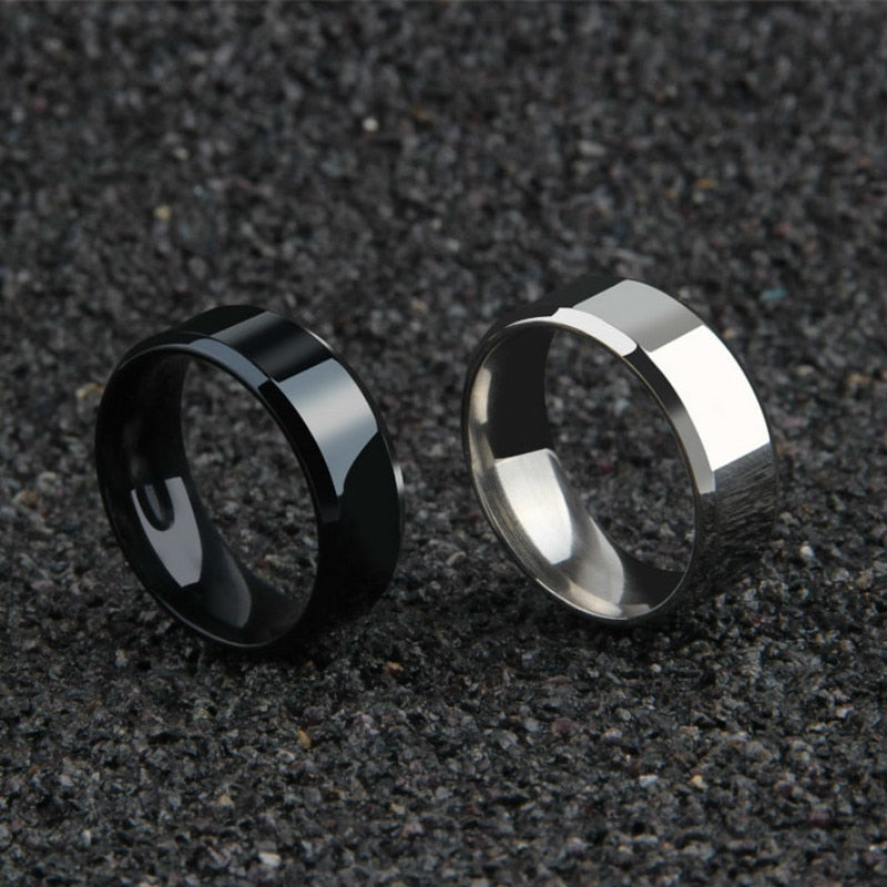 Black and silver minimalist men's band rings 8mm on textured surface.