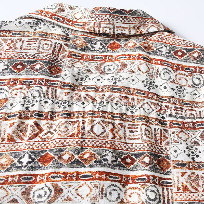 Close-up of Hawaiian print fabric featuring geometric tribal patterns in rust red, black, and cream.
