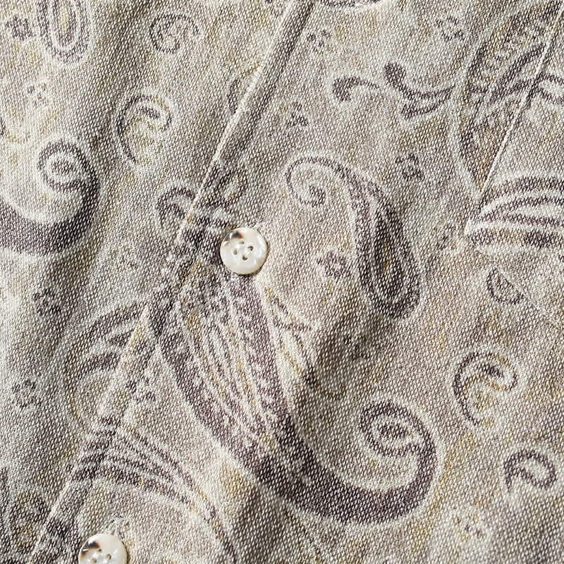 Close-up of button closure and paisley print fabric on men’s summer Cuban collar shirt.
