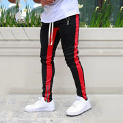 Skinny joggers for men in black with red stripes, paired with white sneakers, stylish outdoor look.