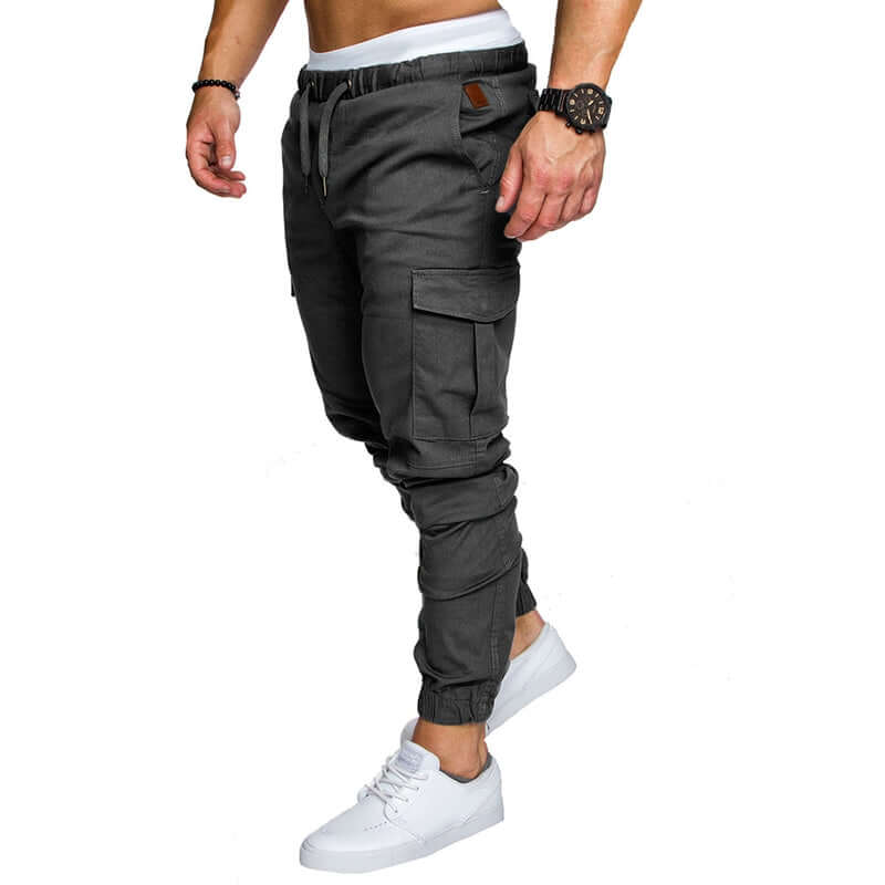 Model wearing slim fir cargo joggers for men in dark gray with white sneakers.