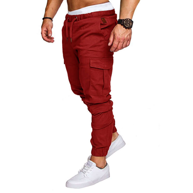 slim fir cargo joggers for men in red color, featuring cargo pockets and cuffed ankles, paired with white sneakers.