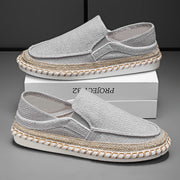 Men’s grey slip-on driving loafers displayed on box with breathable fabric construction
