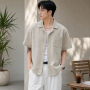 Man wearing apricot textured Cuban collar short sleeve shirt in a casual summer lifestyle setting.
