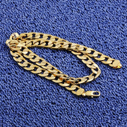 Gold Cuban chain necklace 7mm men's classic link on blue bacjground.