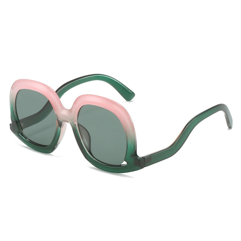 Pink and green oversized oval sunglasses with dark green lenses featuring a colorful fashion-forward design.
