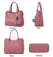 Pink rose embroidery handbag shown in front, side, back, and bottom views, highlighting structured design, gold-tone accents, and durable base studs.
