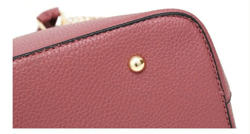  Close-up view of protective metal feet on the bottom of the pink embossed rose handbag