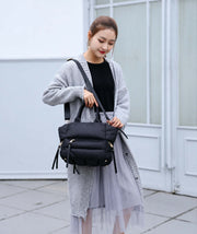 Woman carrying a black winter puffer tote bag with adjustable shoulder strap for everyday casual use.
