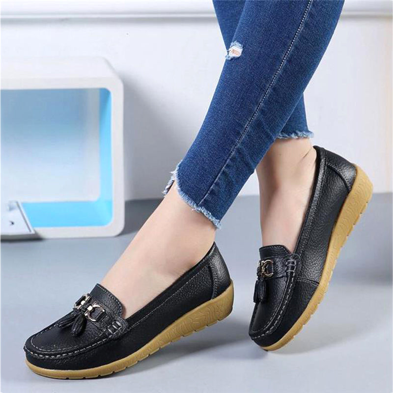 Woman wearing black genuine leather slip-on loafers with classic everyday style.
