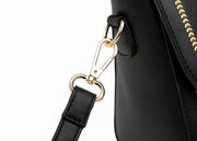 Close-up of detachable shoulder strap hardware on black structured handbag.
