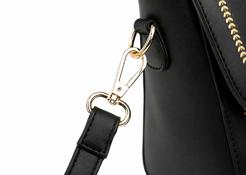Close-up of detachable shoulder strap hardware on black structured handbag.

