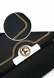 Close-up of gold-tone turn-lock closure and decorative stitching on black handbag.
