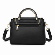 Back view of black structured crossbody handbag with zippered pocket and gold-tone handle.
