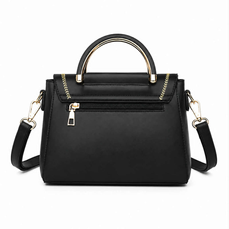 Back view of black structured crossbody handbag with zippered pocket and gold-tone handle.
