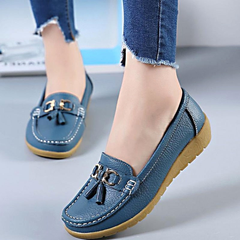 Woman wearing blue genuine leather slip-on loafers with comfortable casual style.
