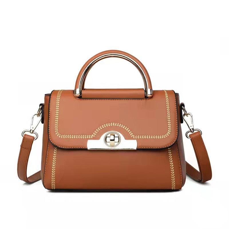 Camel brown structured crossbody handbag with gold-tone handle and elegant detailing.
